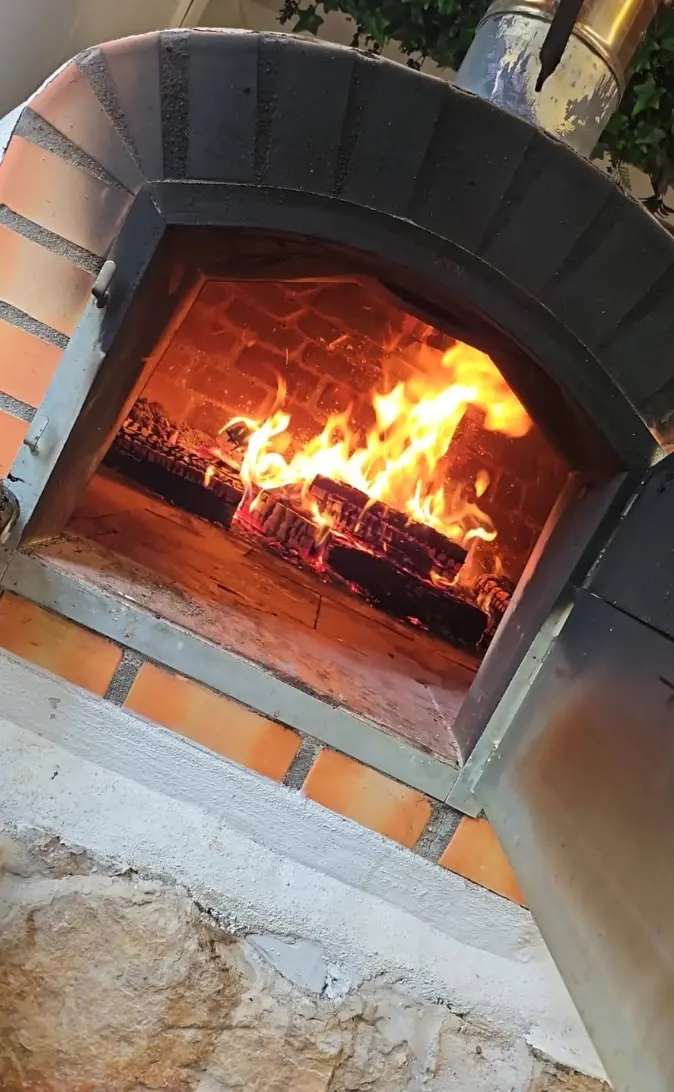 Le four en brique de L'Auberge de la Côte, porte ouverte sur les flammes du feu de bois